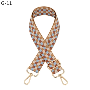 Detail of adjustable plaid shoulder strap with blue checkered pattern and gold metal hooks