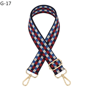 Detail of red and blue checkered woven bag strap with adjustable golden metal buckles