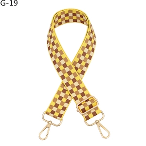 Close-up of adjustable checkerboard bag strap with yellow and brown weave and gold metal hooks