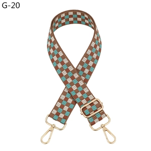 Detail of adjustable plaid bag strap with brown checkerboard pattern and gold metal hooks