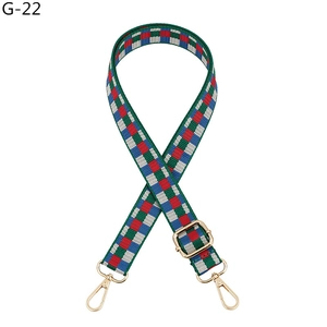 Detail of adjustable plaid woven handbag strap with gold swivel hooks and checkered pattern