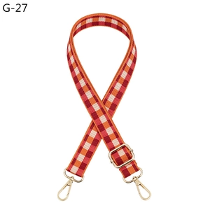 Detail of adjustable plaid woven bag strap in orange and white with gold metal lobster clasps