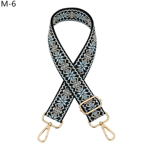 Detail of blue and beige geometric woven bag strap with gold lobster clasps and buckle