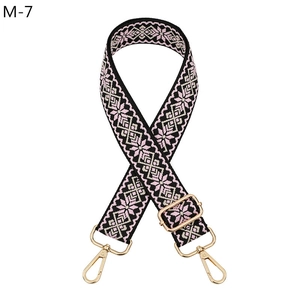 Detail of adjustable floral woven bag strap with pink geometric patterns and gold hooks