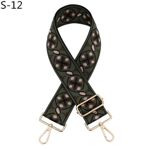 Detailed view of olive green embroidered bag strap with floral patterns and gold metal clips