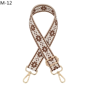 Close-up of ethnic style woven bag strap with brown pattern and golden metal clasps