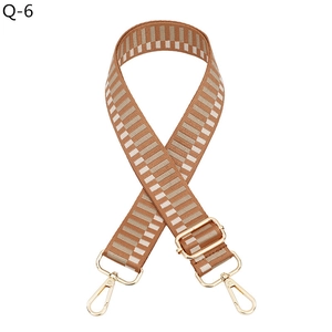 Detail of adjustable geometric woven shoulder strap with gold metal lobster clasps and buckles