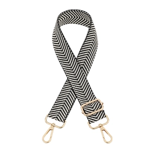Detail of adjustable black and white herringbone bag strap with light gold metal clasps