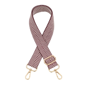 Detail of red and white chevron woven bag strap with adjustable golden metal hardware