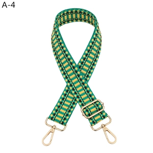 Detail of adjustable woven purse strap with green yellow pattern and gold metal hooks