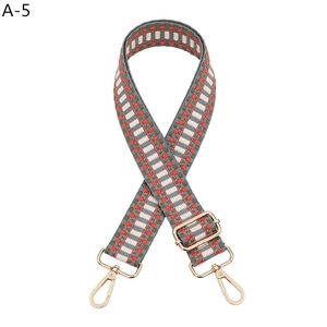 Detail of adjustable woven bag strap with orange geometric pattern and gold metal hooks