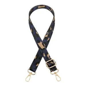 Détail macro de la bandoulière léopard avec mousquetons et boucles en métal doré