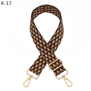 Detail view of the wide woven strap featuring orange geometric scales and gold metal clips