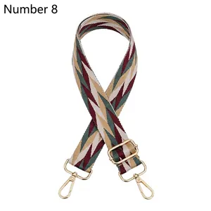Detail view of adjustable bag strap with green and red chevron pattern and gold metal clips