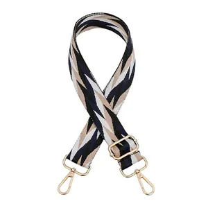 Close-up of geometric striped woven strap with gold metal hooks and adjustable buckle