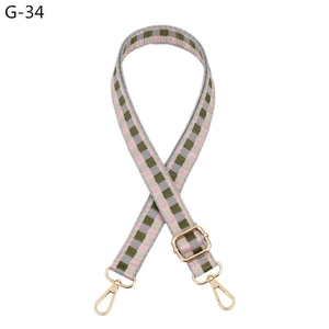 Detail of checkered woven bag strap with golden metal lobster clasps and adjustable buckle