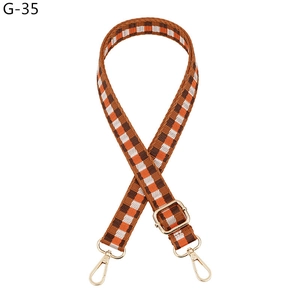 Detail of adjustable woven strap with orange checkerboard pattern and gold hardware