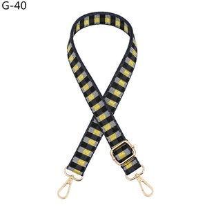 Detail of adjustable yellow and black checkerboard woven bag strap with gold metal hardware
