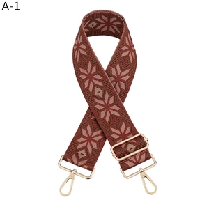 Close-up of red ethnic bag strap with geometric snowflake patterns and gold metal buckles