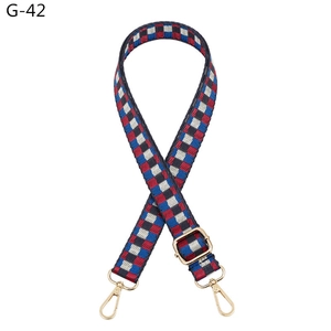 Detail of adjustable woven bag strap with red blue white geometric checkered pattern