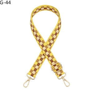 Detail view of adjustable checkered bag strap in yellow and brown with gold hardware