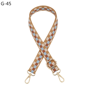 Detail of adjustable woven bag strap with retro checkerboard pattern and gold hardware