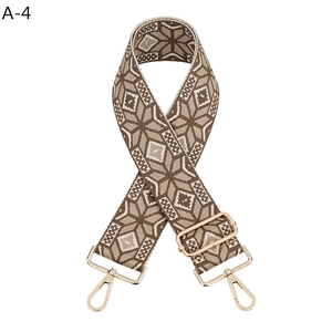 Close-up of ethnic geometric woven bag strap with golden metal lobster clasps and buckles