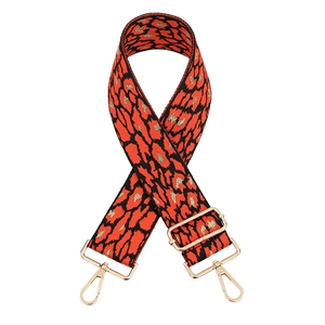 Close-up of red and gold leopard print handbag strap with polished gold metal lobster clasps