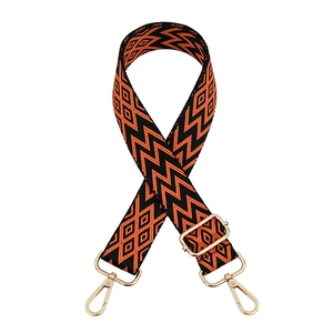 Detail of adjustable orange and black woven shoulder strap with gold metal buckles