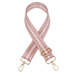 Detail of adjustable woven bag strap in pink with white arrow pattern and gold metal hooks