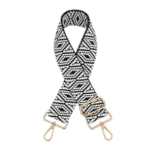 Close-up of woven bag strap with black and white diamond pattern and gold metal hooks