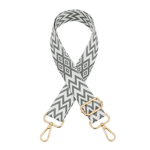 Close-up of gray and white geometric canvas bag strap with golden hardware