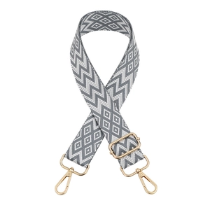 Macro detail of geometric grey and white woven bag strap with golden metal buckle