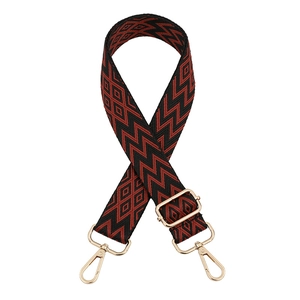 Close-up of adjustable geometric red and black canvas shoulder strap with gold lobster clasps