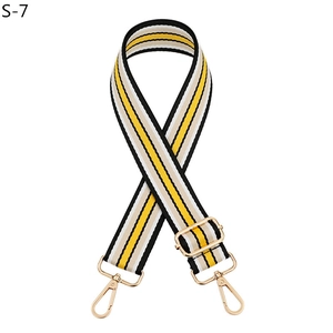 Close-up of adjustable striped canvas bag strap with golden metal carabiner hooks