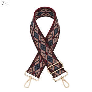 Close-up of geometric pattern woven bag strap with golden metal lobster clasps and slider