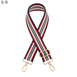Detail showing red, white, and black striped woven bag strap with adjustable gold buckle