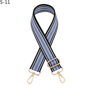Close-up of adjustable striped nylon bag strap with pale gold metal swivel hooks and buckles