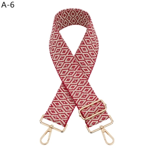 Nahaufnahme des rot-weißen geometrischen Jacquard-Webgurts mit goldenen Metallkarabinern