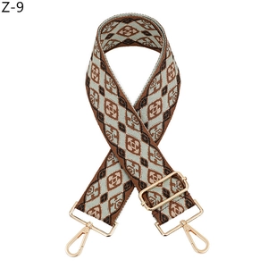 Detailed view of woven geometric bag strap with gold metal buckles and adjustable slider