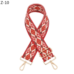 Close-up of adjustable red and beige diamond pattern bag strap with gold metal hooks