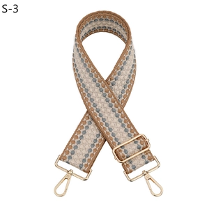 Détail d'une bandoulière tissée réglable avec motif rétro et crochets en métal doré