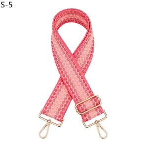 Détail de bandoulière réglable tissée à pois roses avec mousquetons en métal doré