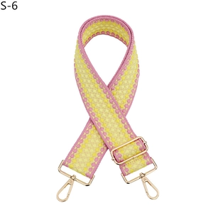 Détail de la bandoulière tissée rose et jaune avec des mousquetons en métal doré clair
