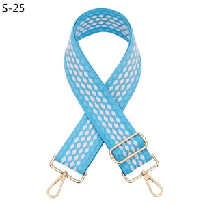 Détail d'une bandoulière tissée large aux motifs bleu blanc rose et mousquetons dorés