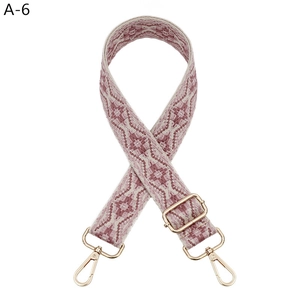 Close-up of rose pink jacquard guitar strap with geometric pattern and gold hardware