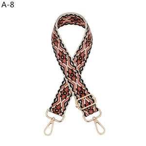 Detail of bohemian geometric woven shoulder strap in orange and black with gold hardware