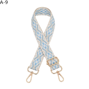 Detail of bohemian jacquard bag strap with blue geometric patterns and gold metal buckles
