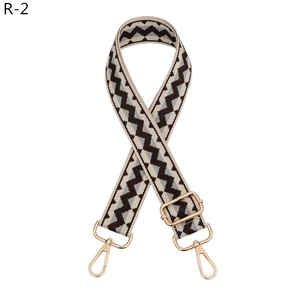Close-up of adjustable woven shoulder strap with geometric patterns and gold metal clasps