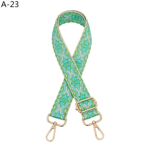Detail of ethnic geometric pattern woven strap with golden metal swivel hooks and buckle